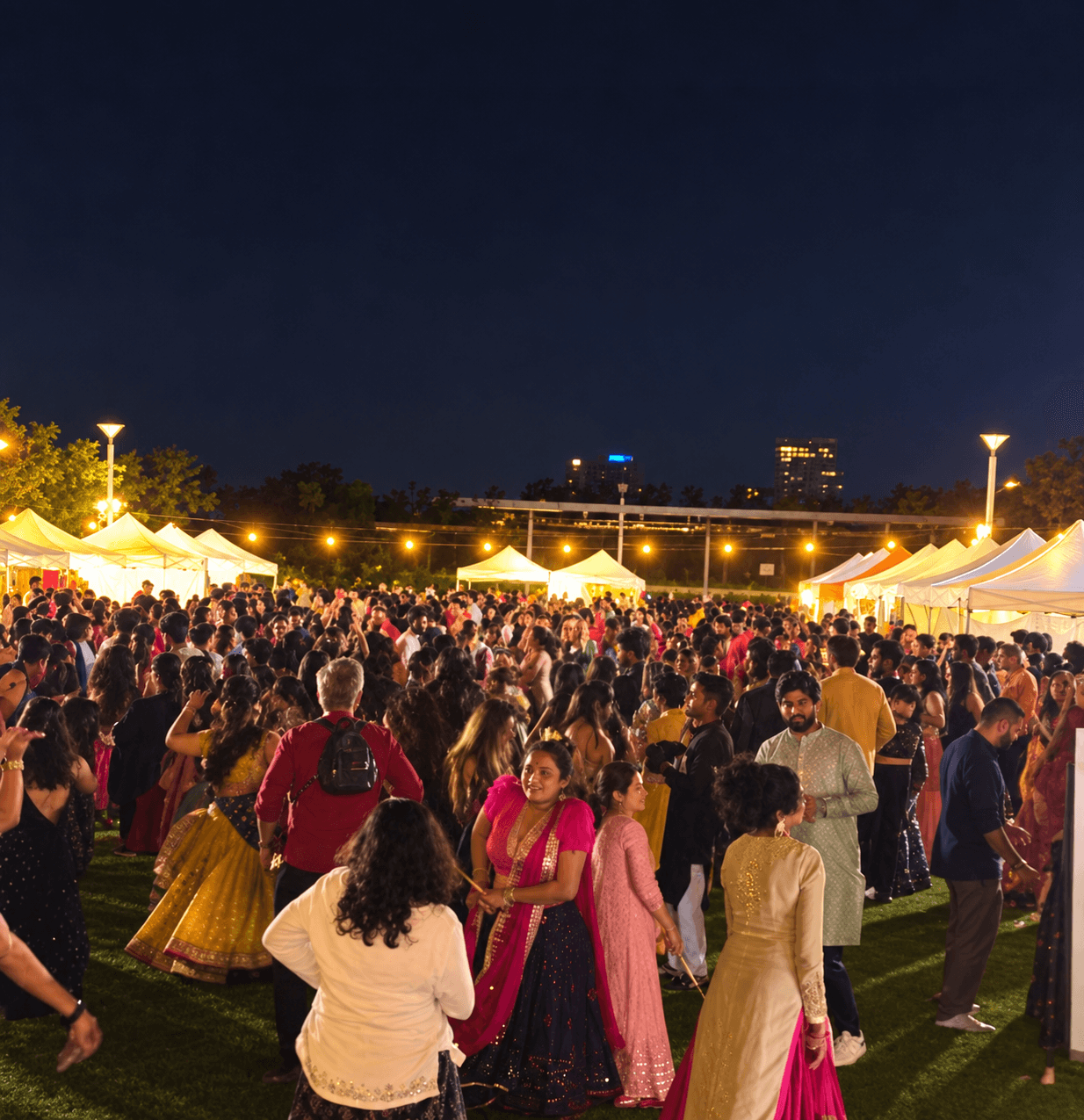 A large Garba crowd celebrating under warm festival lights at Lachlan’s Line Park