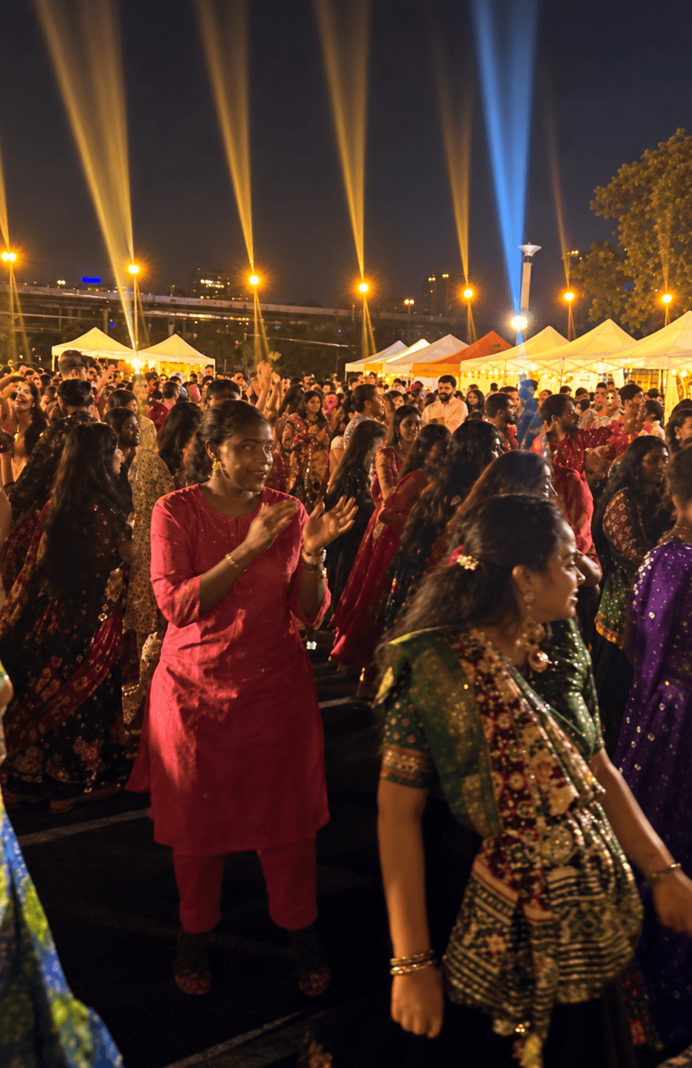 Garba crowd enjoying the celebration beneath golden spotlights