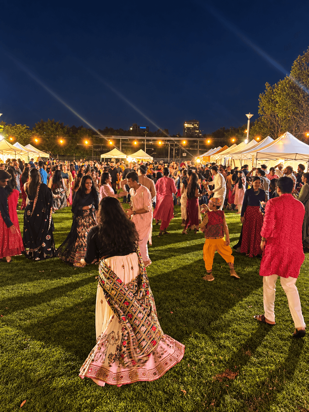 Open-air Garba crowd enjoying the festival beneath the night lights
